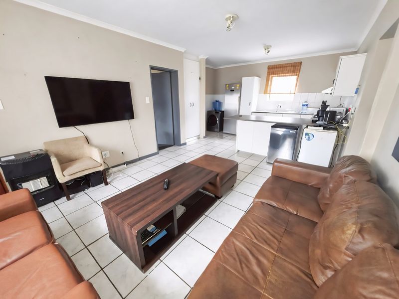 Open-plan living area featuring tiled flooring and a functional kitchen with built-in cabinetry and sink, creating a versatile space for living and dining.