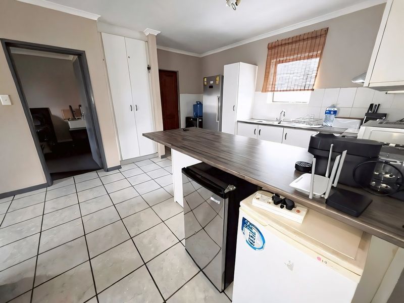 Functional kitchen featuring tiled flooring, laminate countertops, a central island, and ample built-in cabinetry with a dedicated pantry cupboard.