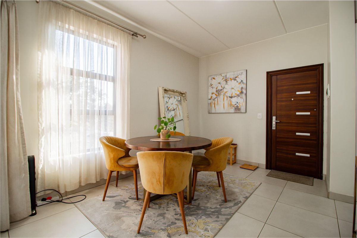 A bright and well-maintained living area featuring large windows, neutral tiled flooring, and a modern timber veneer entrance door.