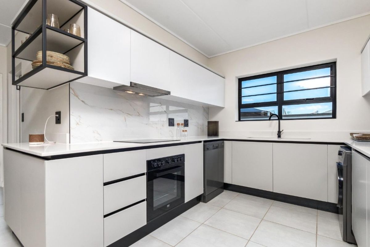 Modern kitchen featuring sleek white cabinetry, marble-look splashback, high-quality black fixtures, integrated appliances, and durable tiled flooring.
