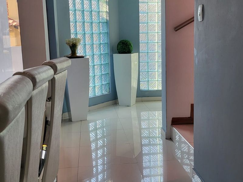 A bright hallway featuring polished porcelain tile flooring, decorative glass block windows, and a modern recessed ceiling design.