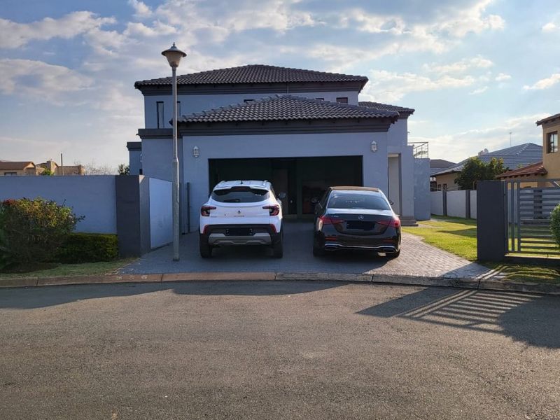 Front elevation of a modern double-story house featuring a double garage, paved driveway, and secure boundary walling.