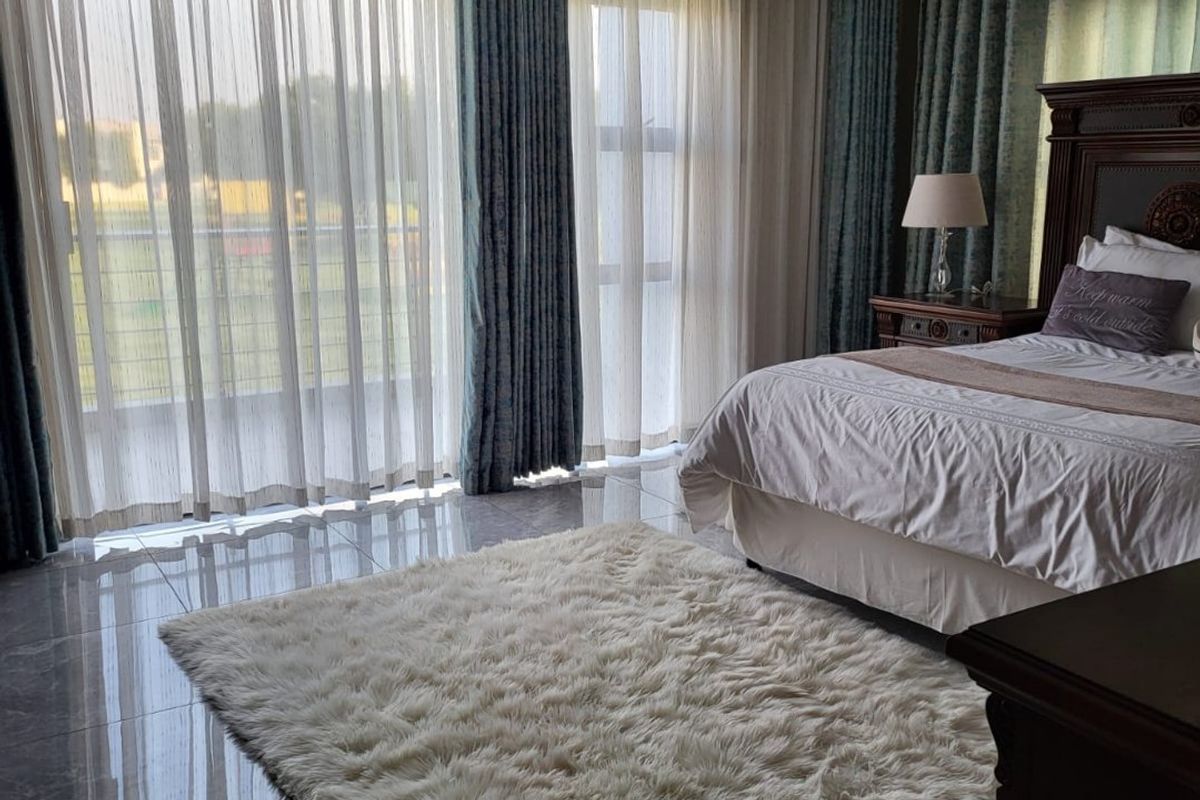 Spacious bedroom featuring polished tiled flooring, recessed lighting, and large sliding glass doors providing access to an outdoor area.