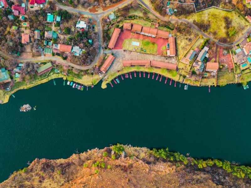 Aerial view of a residential waterfront estate featuring private boat jetties, communal pool facilities, and direct access to the riverbank.