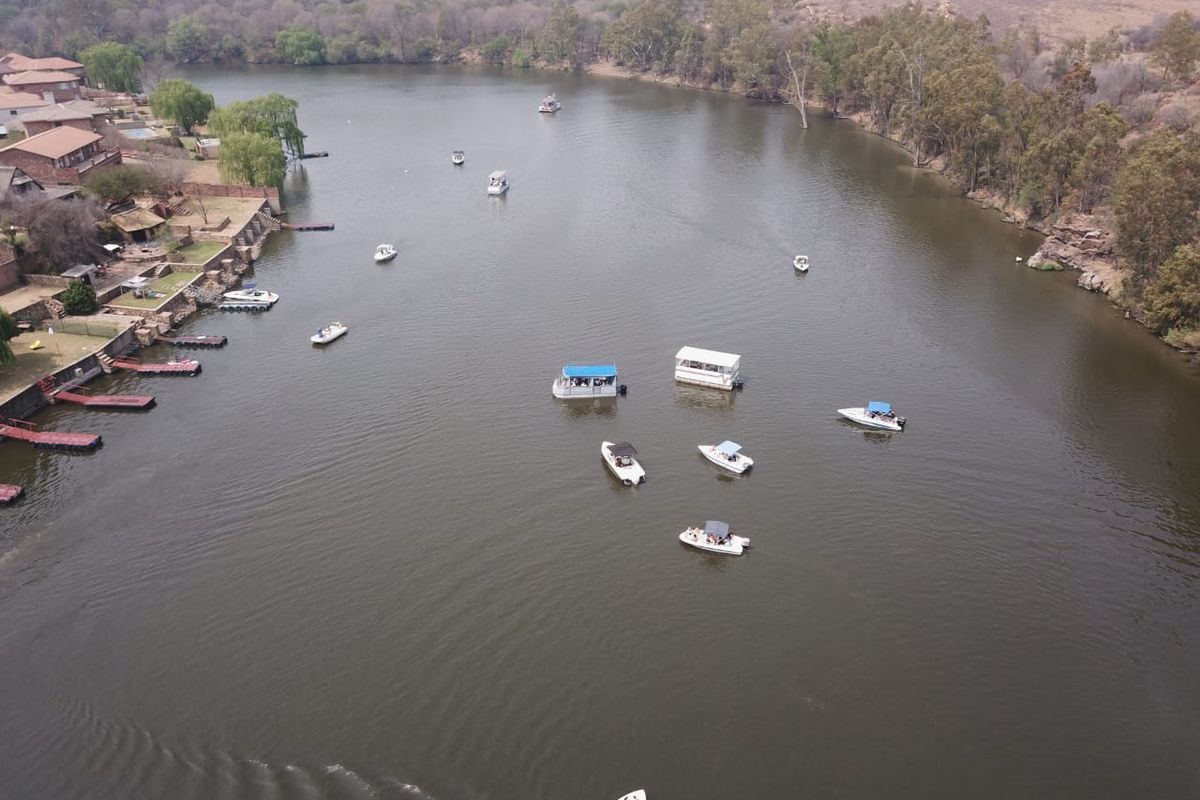 Aerial view of the riverfront area showing residential properties with private jetties and recreational boating activity on the water.