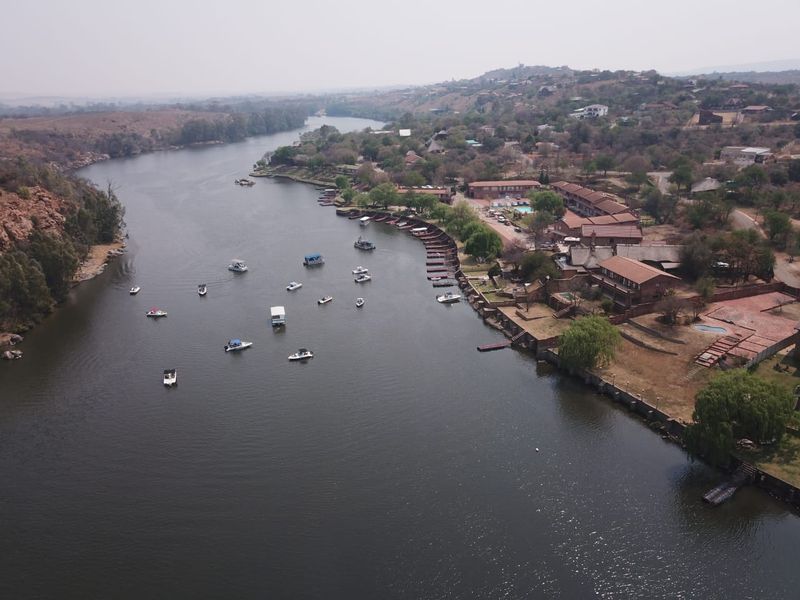 Aerial view of the riverfront property, showcasing direct water access, boat moorings, and the surrounding landscape.