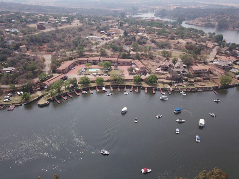 Aerial view of a residential waterfront estate featuring private boat jetties, communal pool facilities, and direct access to the river.