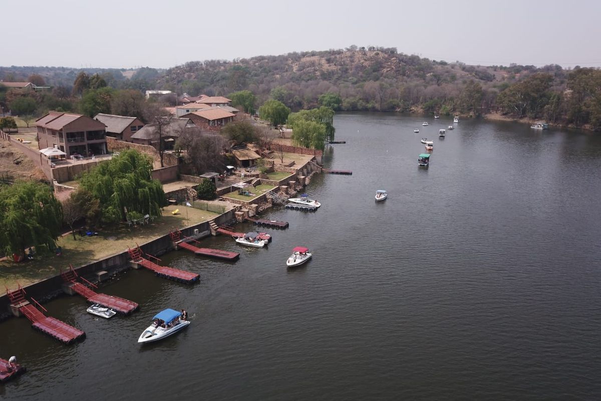 Aerial view of a residential riverfront property featuring private jetties, landscaped gardens, and direct access to the water.