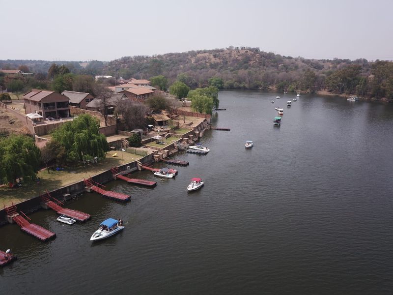 Aerial view of a residential riverfront property featuring private jetties, landscaped gardens, and direct access to the water.