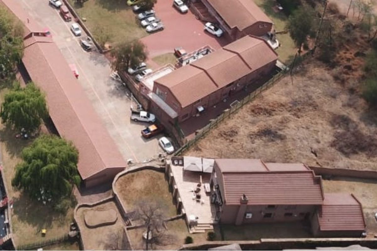 Aerial view of a residential waterfront property featuring multiple boat jetties, paved driveway, and established boundary walls along the riverbank.