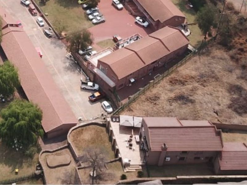 Aerial view of a residential waterfront property featuring multiple boat jetties, paved driveway, and established boundary walls along the riverbank.
