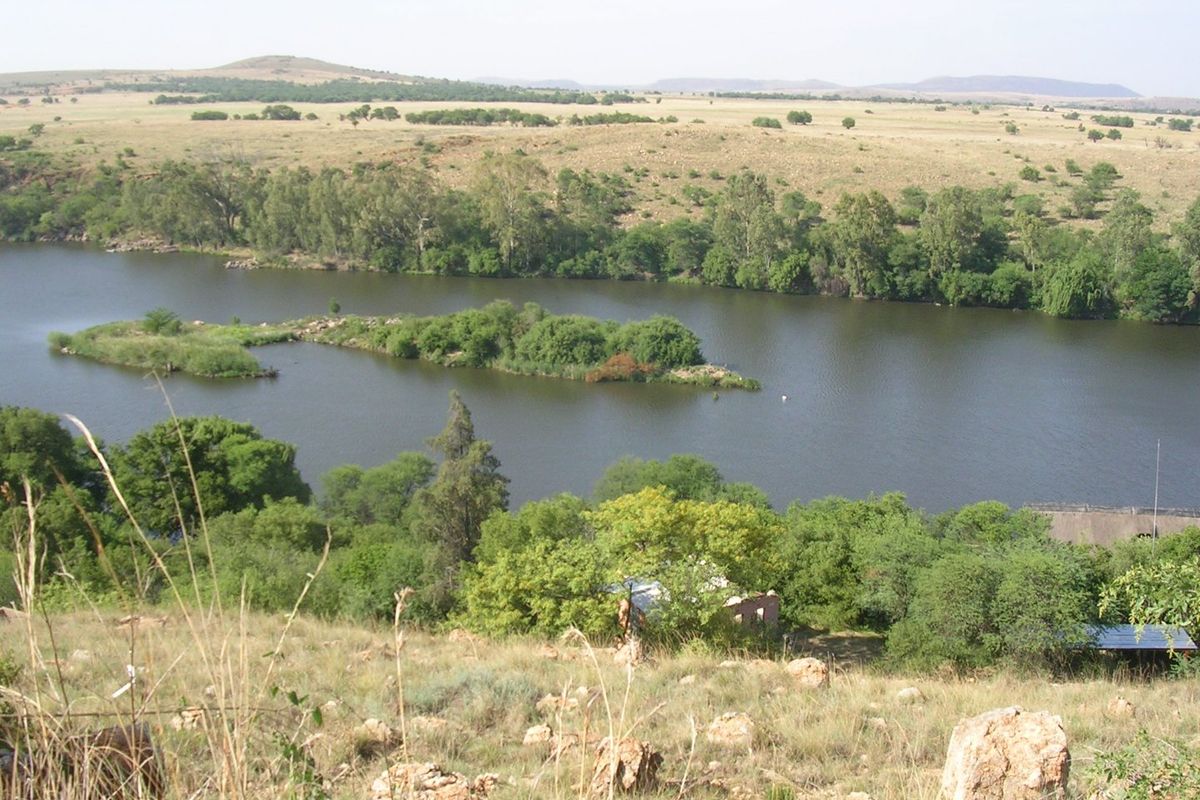 A scenic elevated view overlooking a river with natural vegetation, rocky terrain, and surrounding landscape.