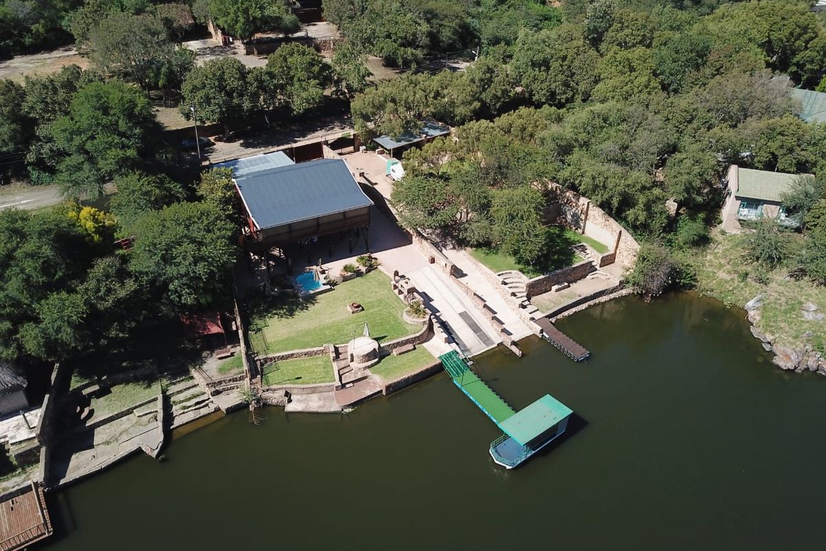 Aerial view of a waterfront property featuring a private boat jetty, slipway, swimming pool, and landscaped garden area.