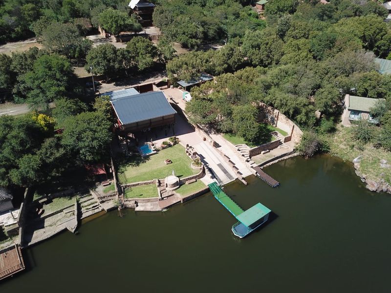 Aerial view of a waterfront property featuring a private boat jetty, slipway, swimming pool, and landscaped garden area.