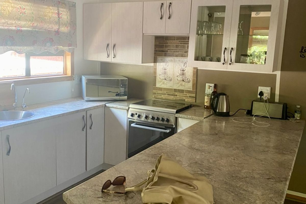 A functional kitchen featuring laminate countertops, built-in oven with cooktop, ample cabinetry, and a tiled splashback, offering a practical layout for daily meal preparation.