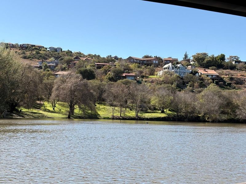 A scenic view overlooking a river with a hillside residential area in the background.