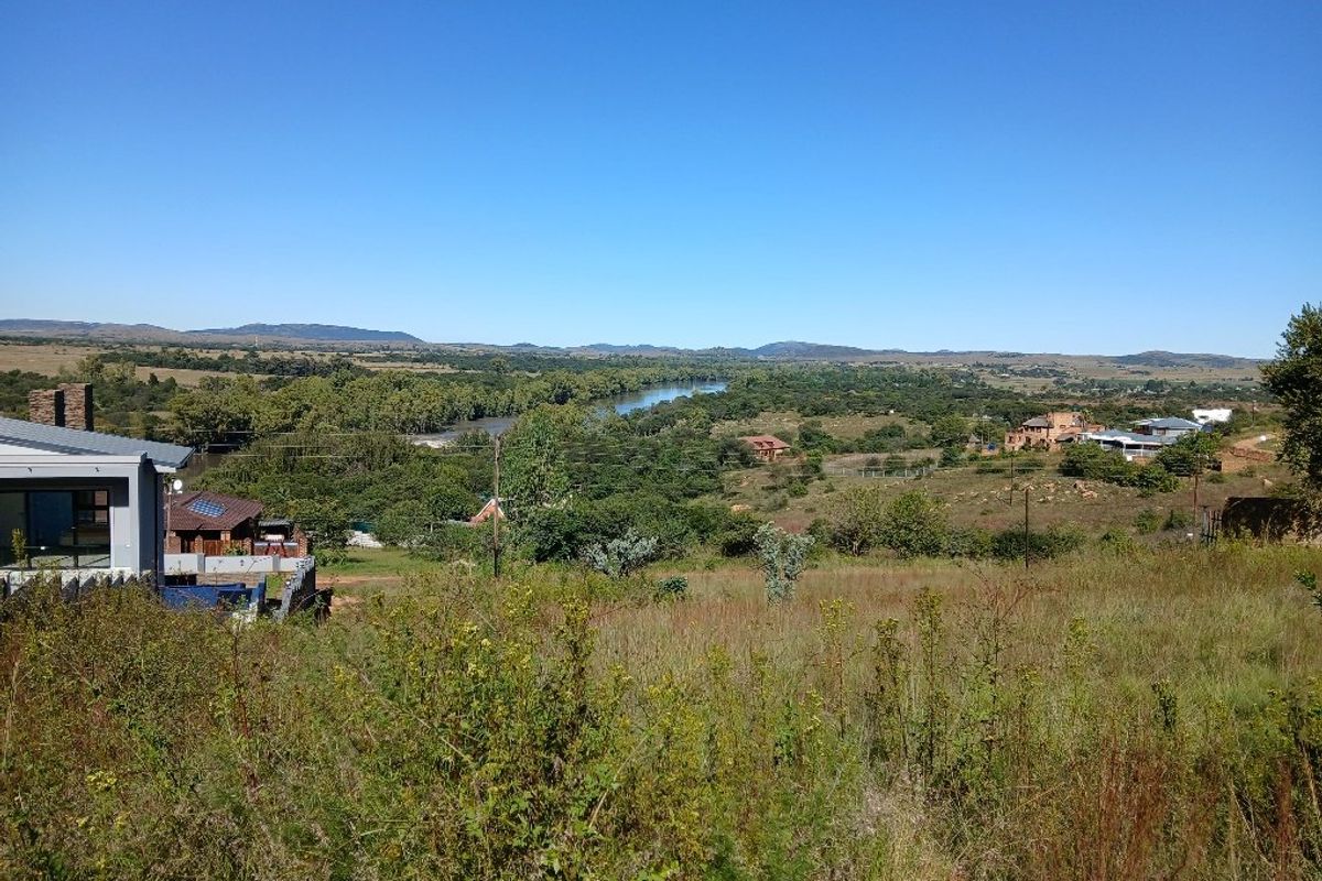 A scenic elevated view overlooking a river, surrounding natural landscape, and distant residential properties.