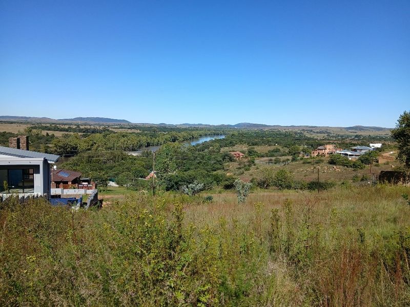 A scenic elevated view overlooking a river, surrounding natural landscape, and distant residential properties.