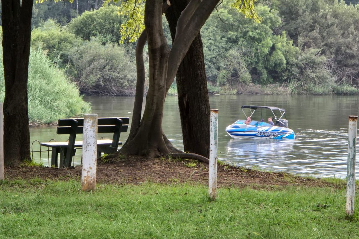 A scenic view of the riverfront featuring mature trees and direct access to the water, ideal for recreational activities.