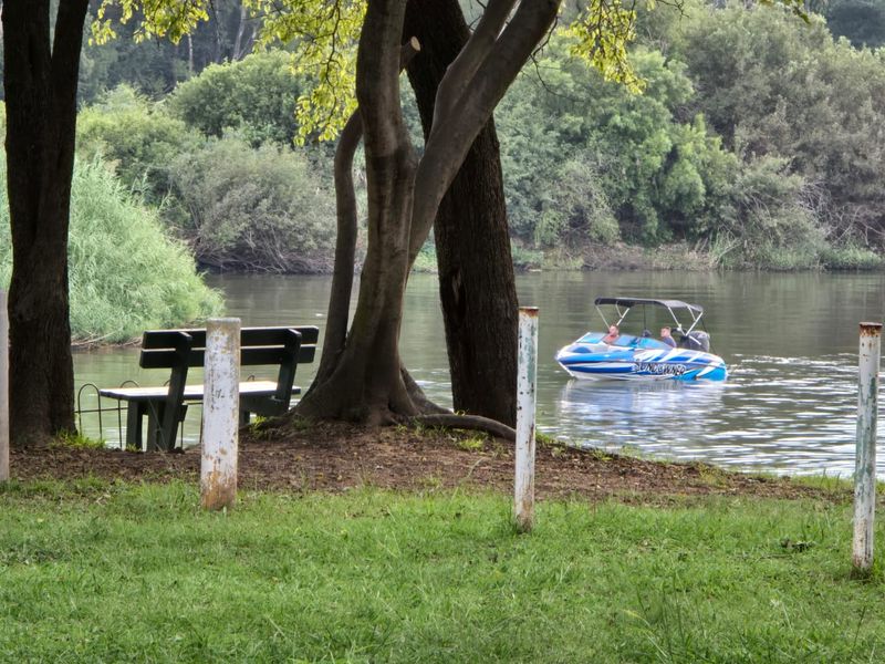 A scenic view of the riverfront featuring mature trees and direct access to the water, ideal for recreational activities.