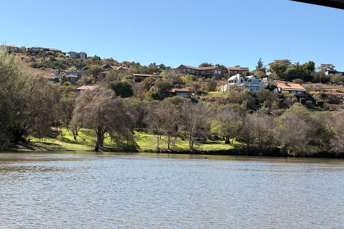 A scenic view overlooking a river with residential properties nestled on the hillside in the background.