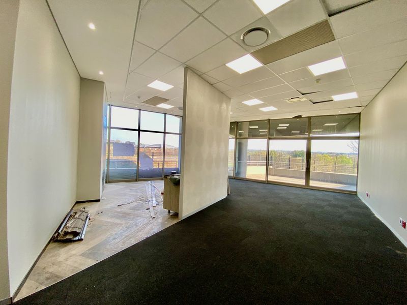 An open-plan office space featuring large windows, carpeted flooring, and a suspended ceiling, currently vacant and ready for custom fit-out.