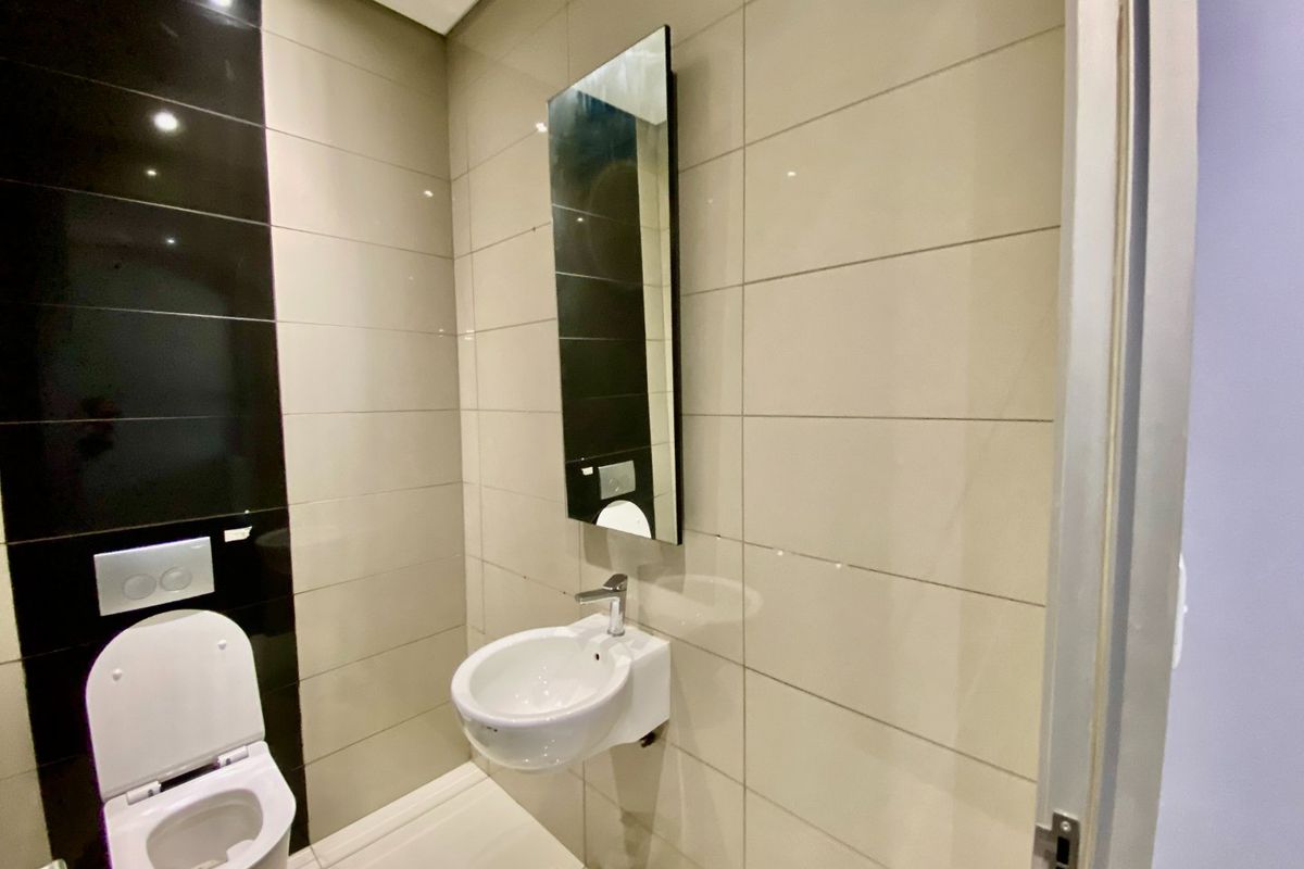 A modern, compact guest bathroom featuring sleek wall-mounted sanitaryware, high-contrast ceramic tiling, and a minimalist basin with chrome fixtures.