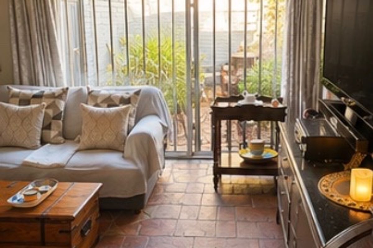 A cozy living room featuring tiled flooring and a large sliding glass door with security bars, providing direct access to the outdoor area.