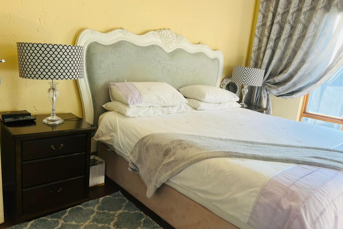 A bedroom featuring a decorative headboard and window curtains.