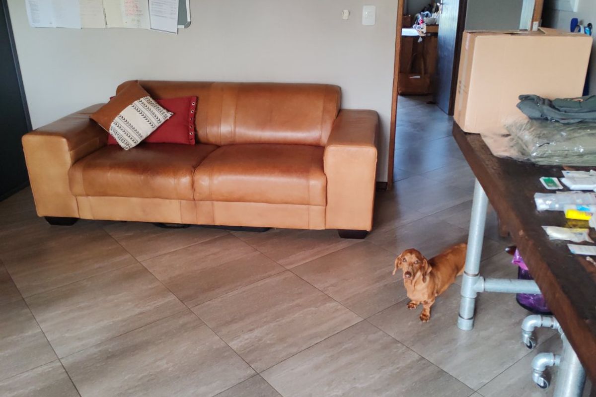 A living area featuring neutral tiled flooring and a doorway leading to an adjacent room.