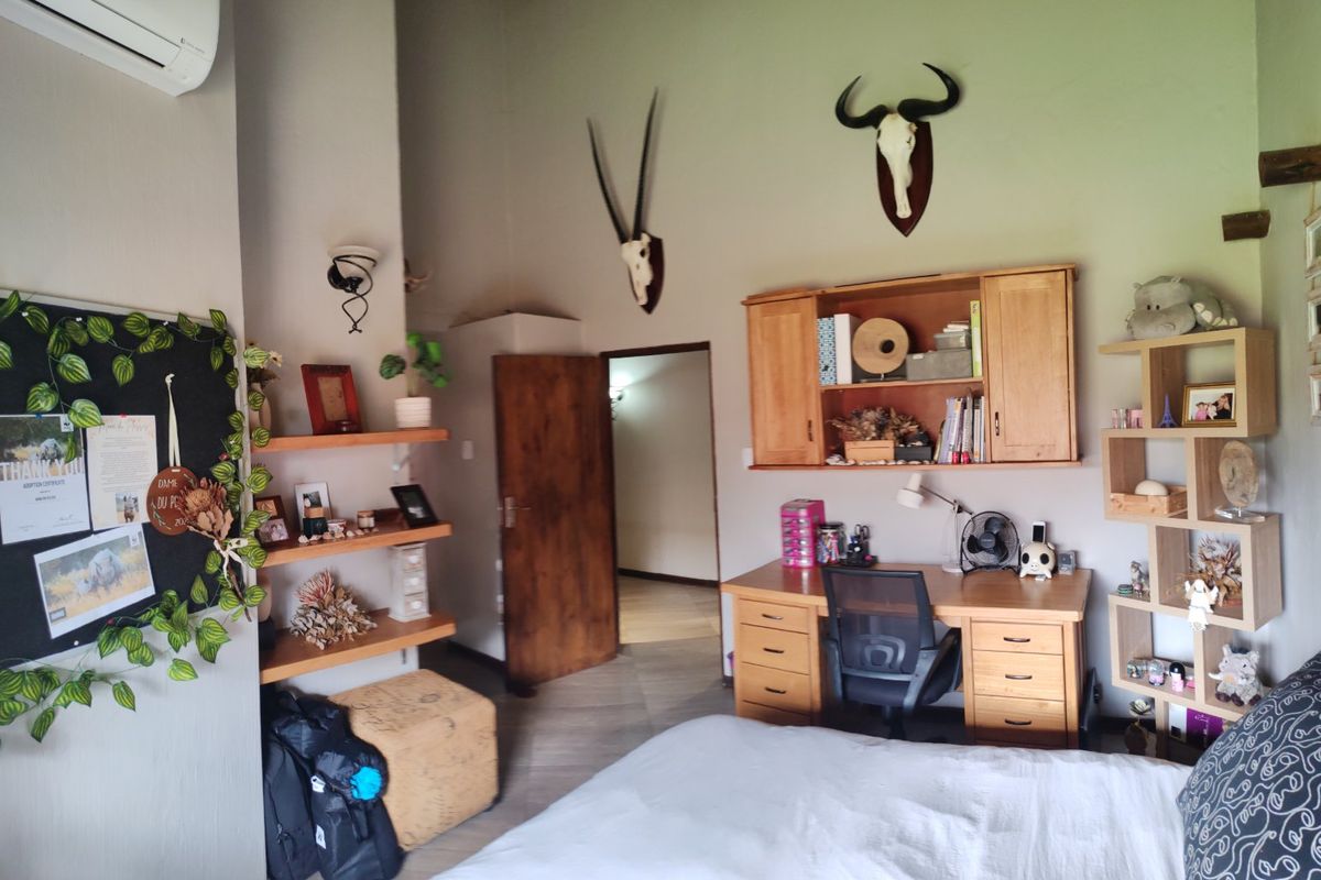 A bedroom featuring tiled flooring, built-in wooden shelving, and a wall-mounted air conditioning unit.