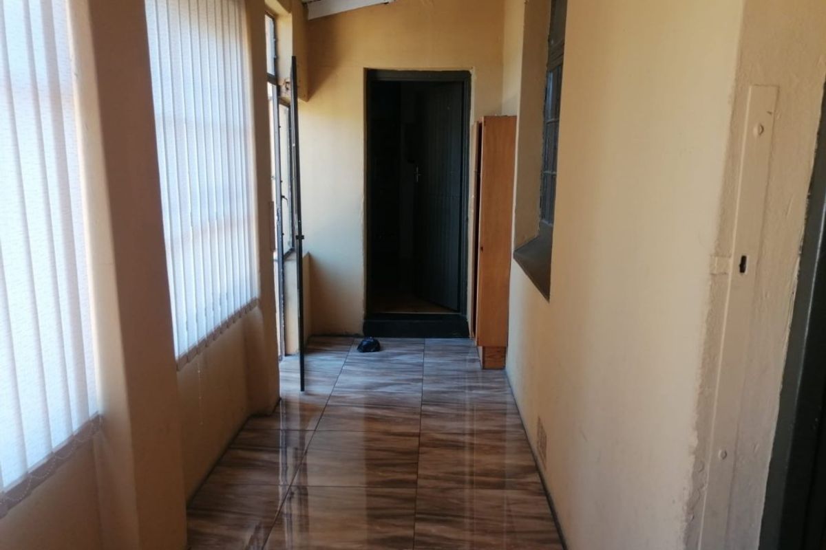 A covered patio or enclosed walkway featuring tiled flooring, vertical blinds, and access to the main interior living space.