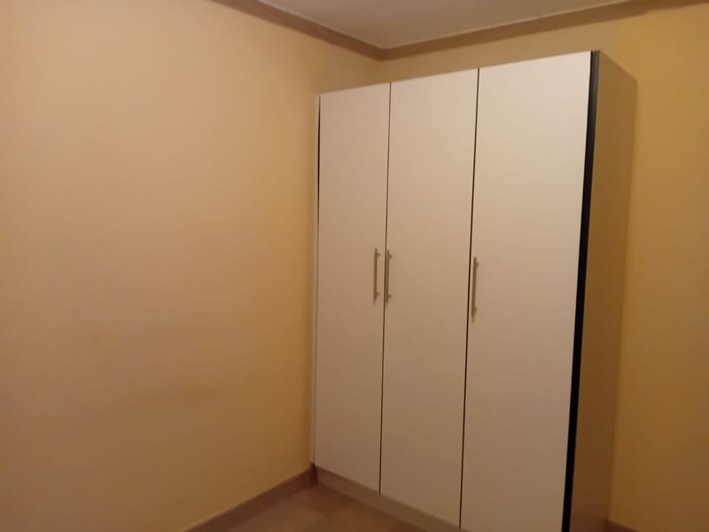 A simple bedroom featuring a white built-in wardrobe with modern handles, providing ample storage space.