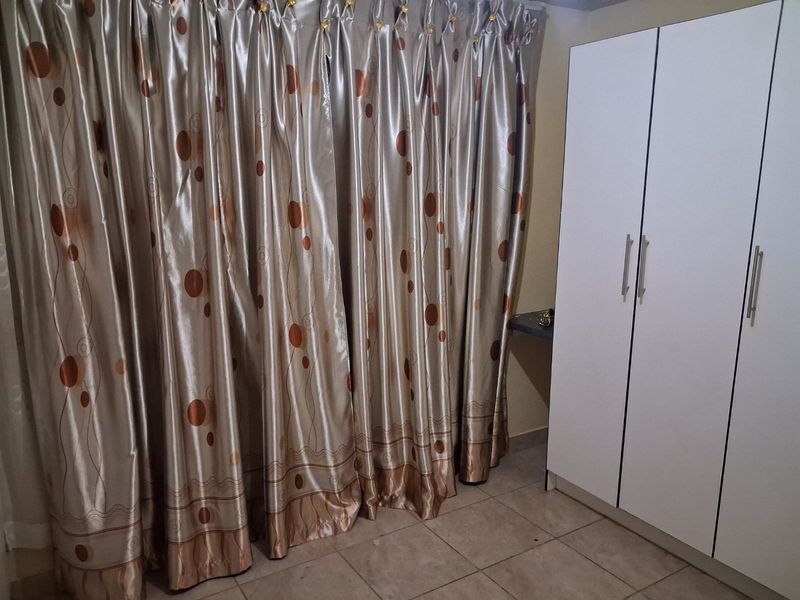 Bedroom featuring tiled flooring and a white built-in wardrobe with modern handles.