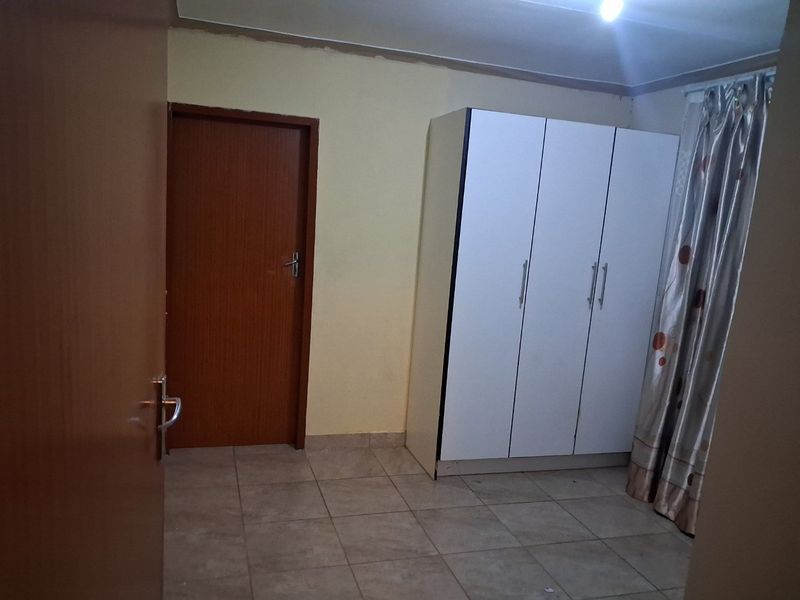 A bedroom featuring tiled flooring and a built-in wardrobe, requiring minor cosmetic updates to the wall and ceiling finishes.