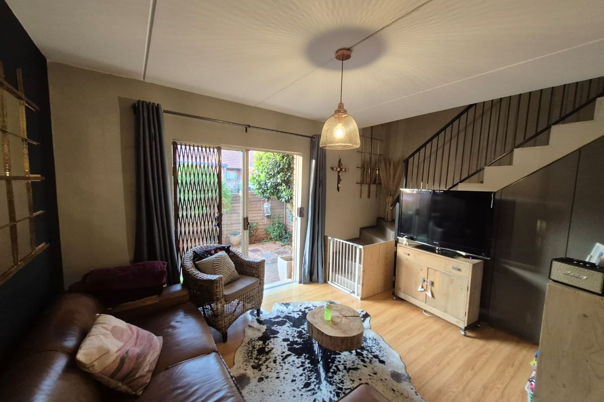 A cozy living room featuring laminate flooring, a staircase with metal railings, and sliding glass doors providing access to the rear outdoor area.