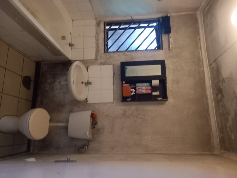 A dated bathroom featuring a bathtub, pedestal basin, and toilet, requiring significant renovation and wall surface repairs to restore functionality and hygiene.