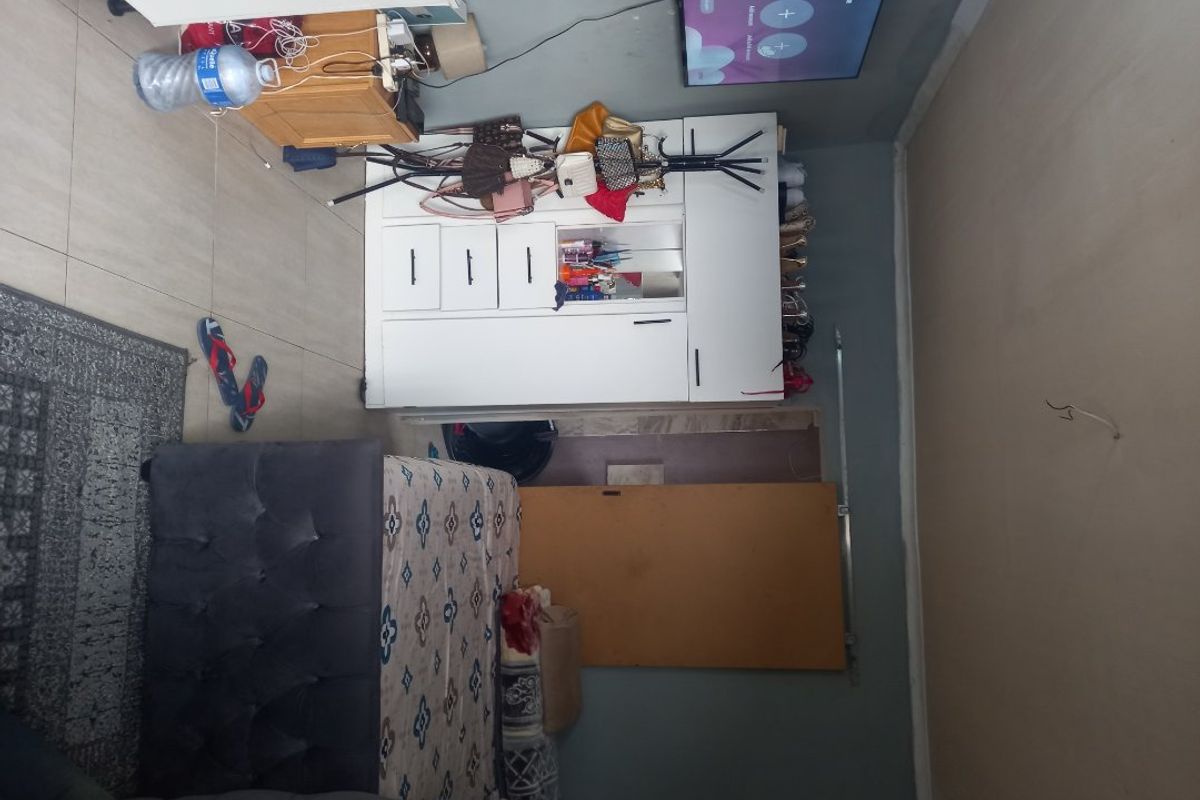 A bedroom featuring tiled flooring and a built-in wardrobe, currently requiring attention to ceiling wiring and wall finishes to improve the overall presentation.