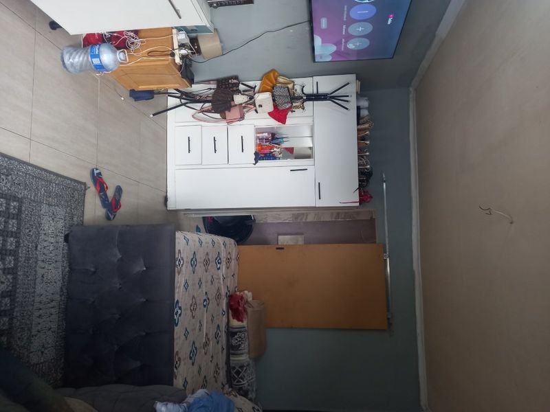 A bedroom featuring tiled flooring and a built-in wardrobe, currently requiring attention to ceiling wiring and wall finishes to improve the overall presentation.