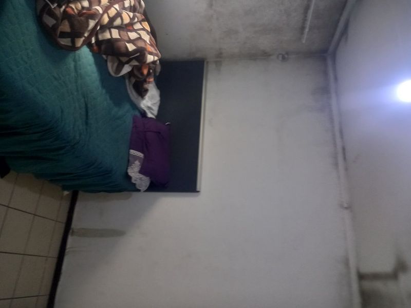 A bedroom featuring tiled flooring, currently showing significant signs of wall and ceiling staining and moisture damage requiring maintenance and repair.