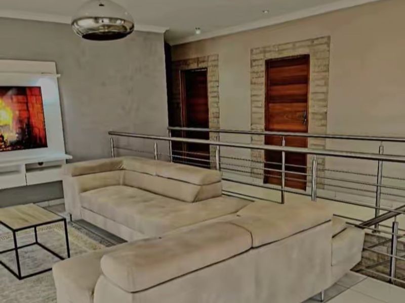 A modern living area featuring tiled flooring, a stainless steel balustrade, and a built-in media unit with recessed lighting.