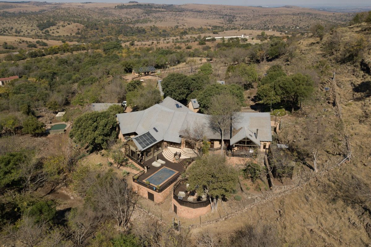 Aerial view of a large farm property featuring a multi-wing residence, swimming pool, solar energy installation, and extensive surrounding landscape.