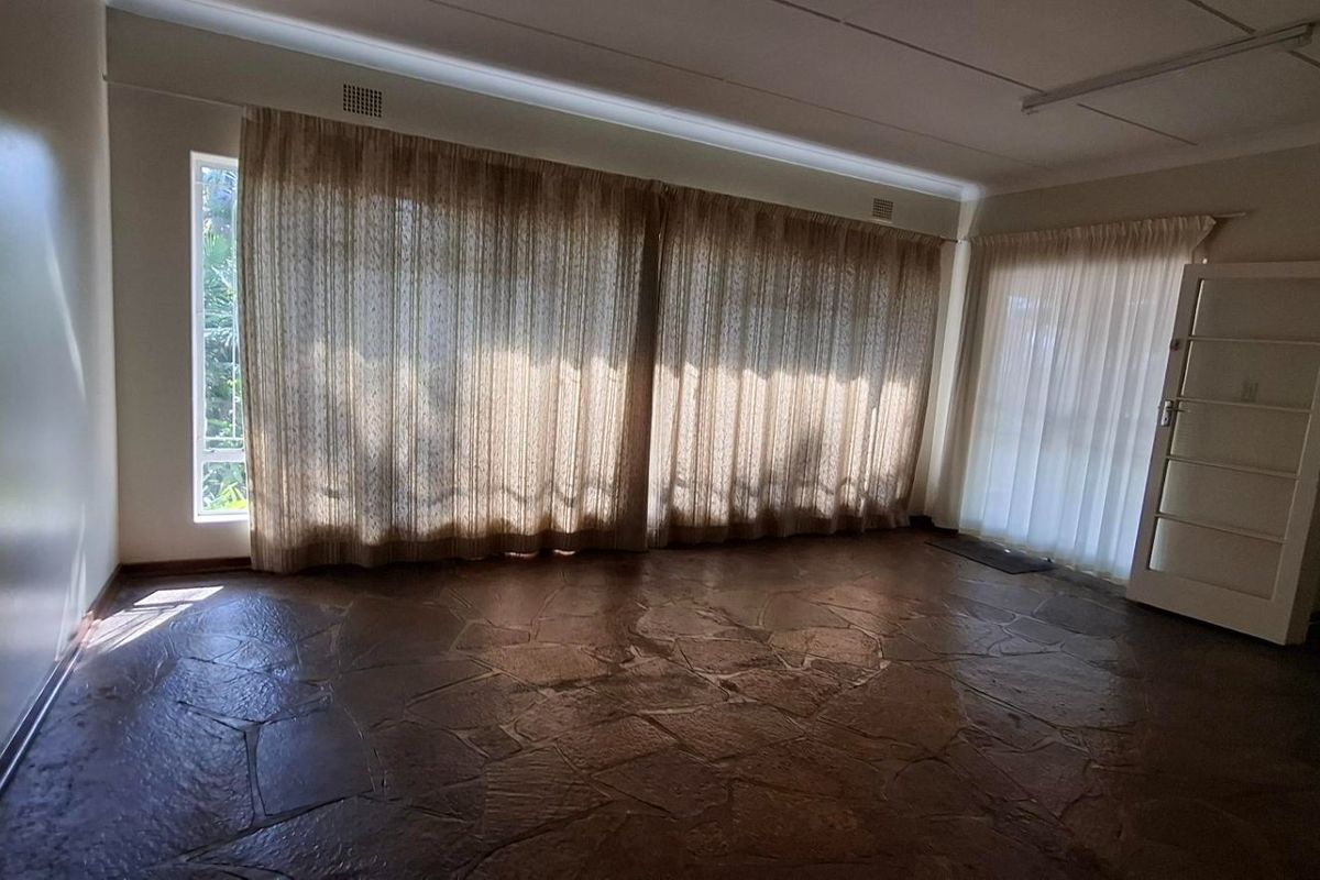 Spacious living area featuring unique flagstone flooring, large windows with natural light, and direct access to an outdoor space.