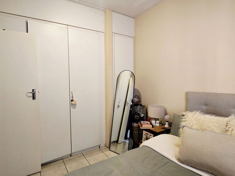 A bedroom featuring built-in cupboards and tiled flooring, providing functional storage space.