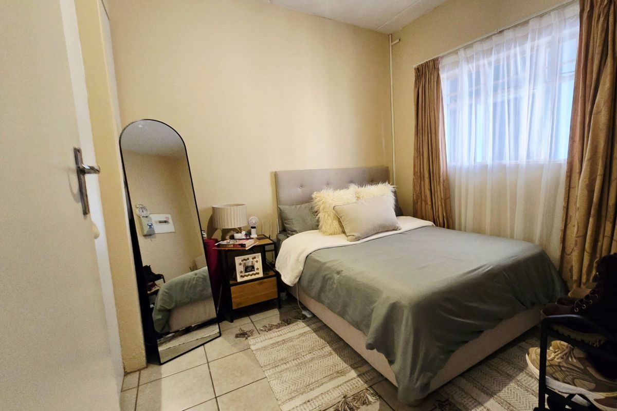 A compact bedroom featuring tiled flooring and neutral wall finishes, providing a functional space with natural light through the window.