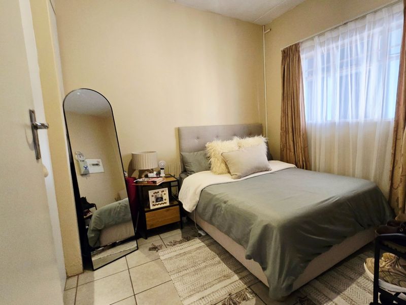 A compact bedroom featuring tiled flooring and neutral wall finishes, providing a functional space with natural light through the window.
