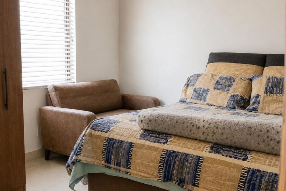 A bedroom featuring tiled flooring, venetian blinds, and an exposed timber and corrugated metal ceiling structure.