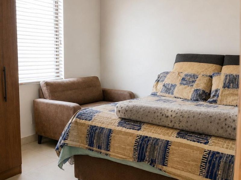A bedroom featuring tiled flooring, venetian blinds, and an exposed timber and corrugated metal ceiling structure.