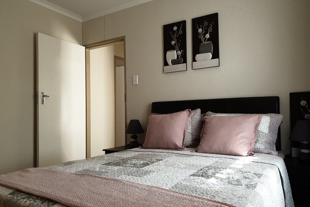A neutrally decorated bedroom featuring coving and a doorway leading to an adjacent space.