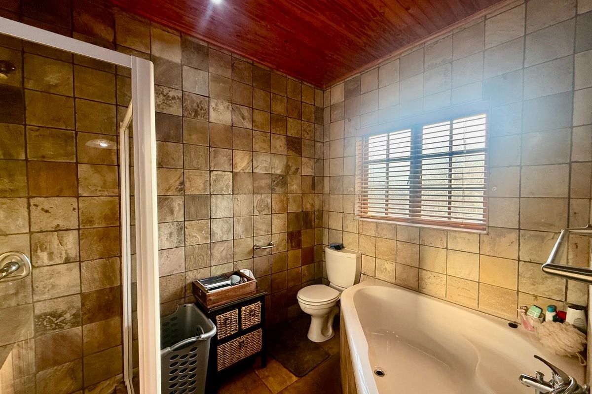 A bathroom featuring a corner bathtub, separate shower enclosure, tiled walls, and a timber ceiling.